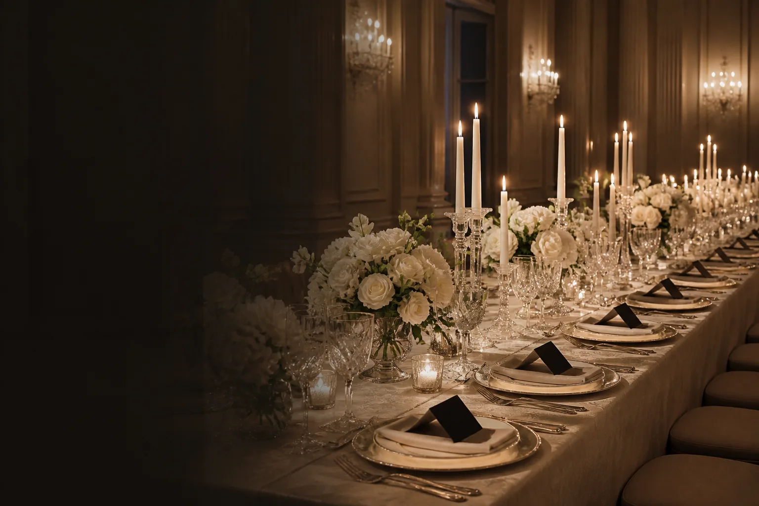 Formal wedding reception tablescape with ivory flowers, crystal, and candlelight